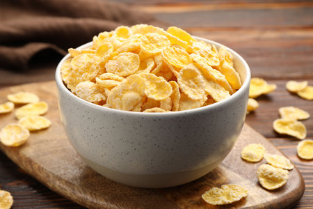 Tasty corn flakes in bowl on wooden table, closeup