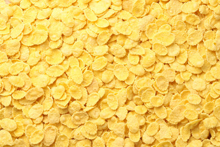Many tasty corn flakes as background, top view