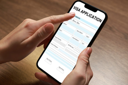 Woman using laptop to fill in online visa application form at table, closeup