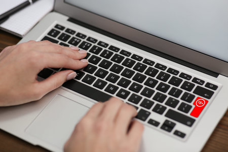 Woman using laptop with red button 18 plus at table, closeup.