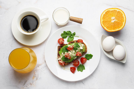 Healthy breakfast with delicious avocado toast served on white marble table, flat lay