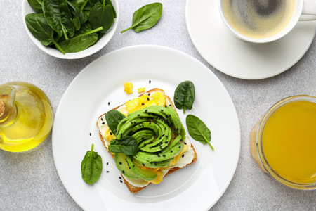 Tasty breakfast with avocado toast served on light grey table, flat lay