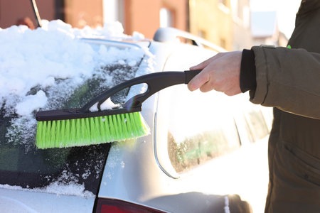 Man cleaning snow from car outdoors on winter day, closeup