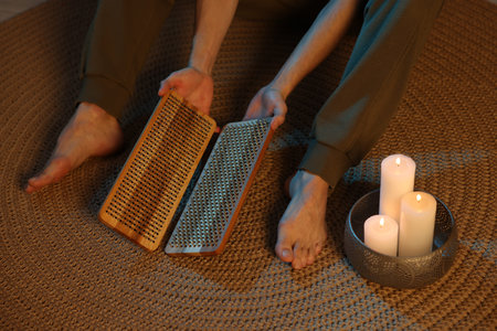 Man with sadhu boards near burning candles on wicker mat, closeup