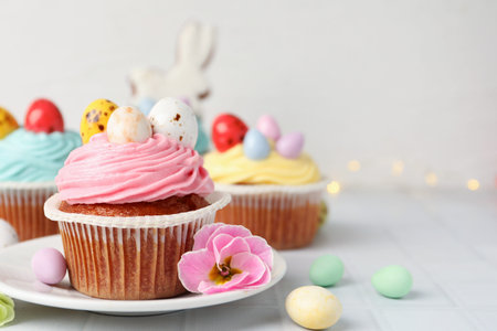 Tasty cupcakes with Easter decor on white table, closeup. Space for text
