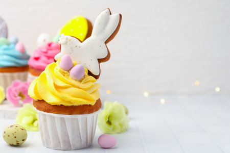 Tasty cupcakes with Easter decor on white table, closeup. Space for text