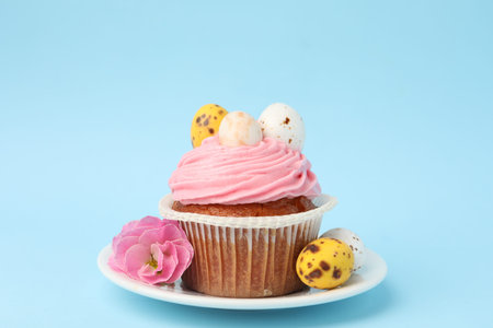 Tasty cupcake with Easter decor on light blue background, closeup