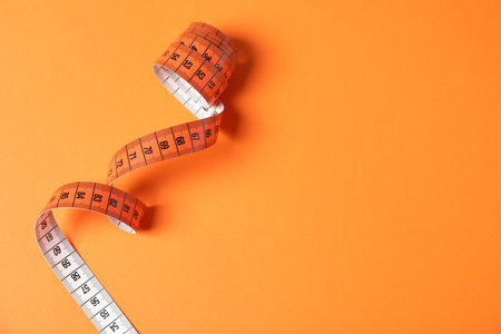 One measuring tape on orange background, top view. Space for text