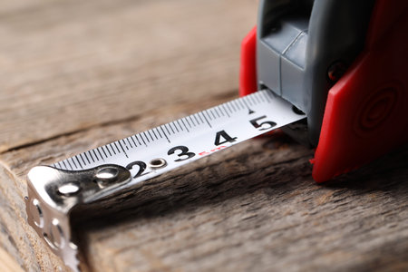 One measuring tape on wooden table, closeup
