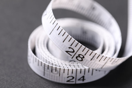 One measuring tape on black background, closeup