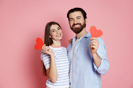 Romantic date. Lovely couple with red paper hearts on pink background