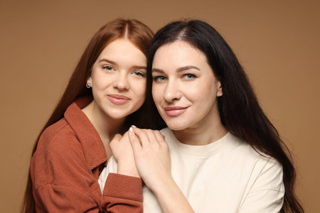 Portrait of mother and her teenage daughter on beige background