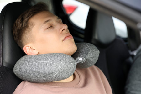 Man with neck pillow sleeping in car
