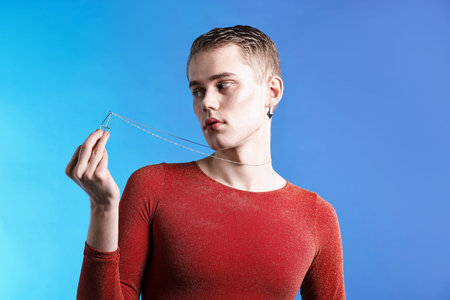 Young man with piercings on light blue background