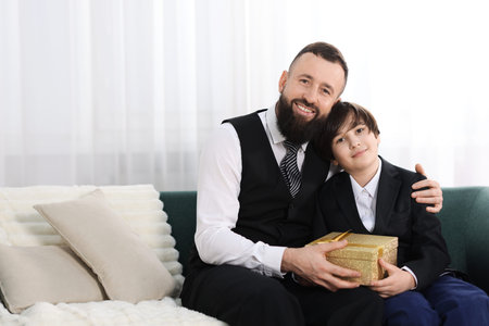 Cute boy greeting his father with gift at home. Space for textの写真素材