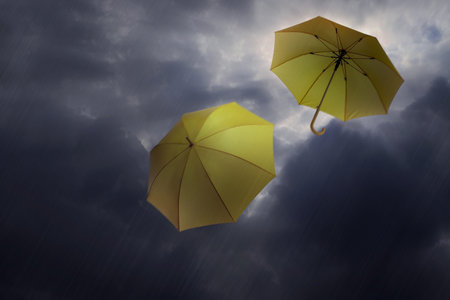 Umbrellas flying in dark cloudy sky. Stormy weatherの写真素材
