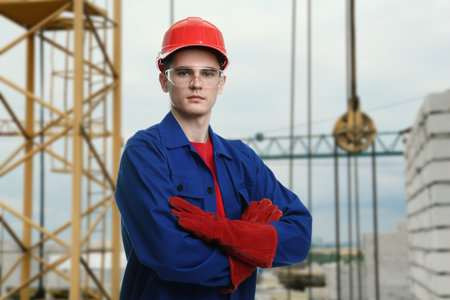 Builder in workwear with hard hat and protective goggles at construction site