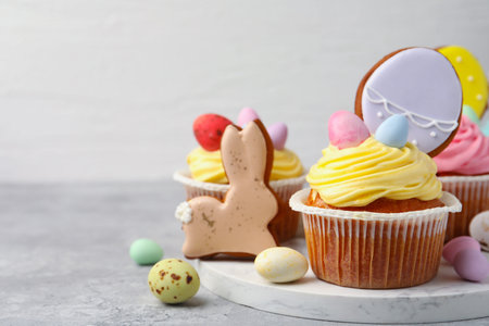 Tasty cupcakes with Easter decor on grey table, closeup. Space for text