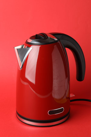 Modern electric kettle on red background. Household applianceの写真素材