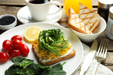 Tasty breakfast with avocado toast served on wooden table, closeup