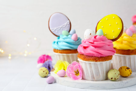 Tasty cupcakes with Easter decor on white table, closeup. Space for text
