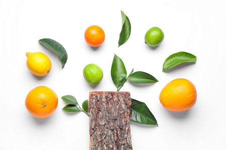 Different fresh citrus fruits, green leaves and tree bark on white background, flat layの写真素材