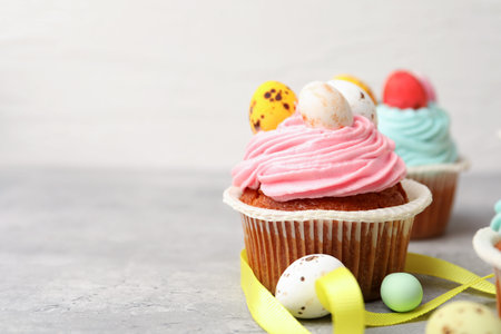 Tasty cupcakes with Easter decor on grey table, closeup. Space for text