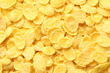 Many tasty corn flakes as background, top view