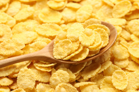 Tasty corn flakes and wooden spoon, closeup