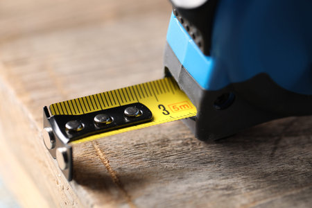 One measuring tape on wooden table, closeup