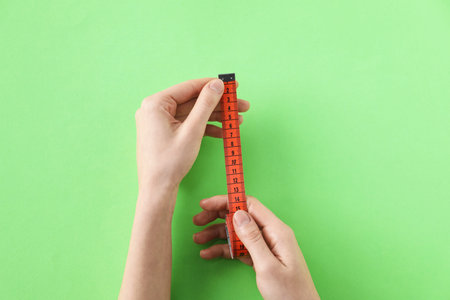 Woman with measuring tape on green background, top viewの写真素材