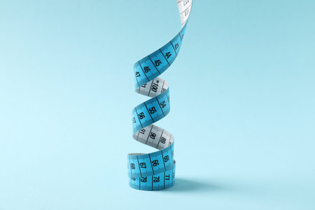 One measuring tape on light blue background, closeupの写真素材
