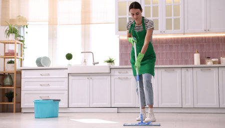 Cleaning service worker mopping floor in kitchen, space for textの写真素材