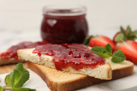 Toasts with butter, sweet jam and mint on table, closeup