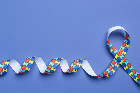 Autism. Colorful puzzle ribbon on blue background, top view. Space for text