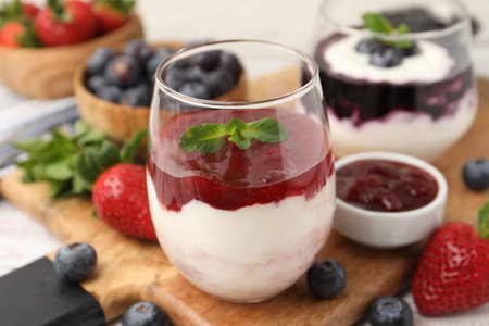 Tasty yogurt with berries, jam and mint on wooden table, closeupの写真素材