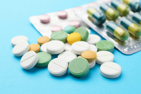 Many different pills on light blue background, closeup