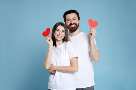 Romantic date. Lovely couple with paper hearts on light blue background