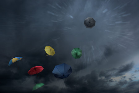 Umbrellas flying in dark cloudy sky. Stormy weather