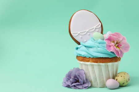 Tasty cupcake with Easter decor on turquoise background, closeup. Space for text