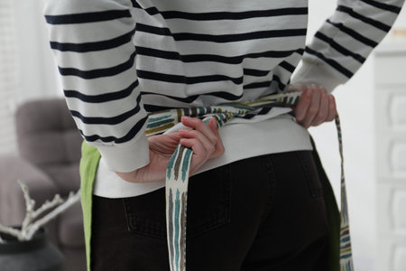 Woman tying clean apron at home, closeupの写真素材