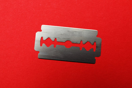 One sharp blade on red background, top view