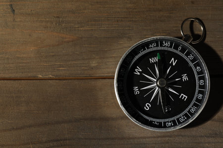 One compass on wooden table, top view. Space for text