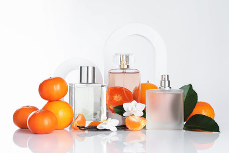 Stylish presentation of aromatic perfume in bottles, fresh tangerines, vanilla pods and orchid...