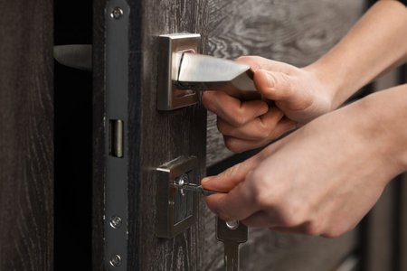 Woman opening wooden door with key indoors, closeup