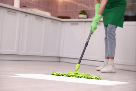 Cleaning service worker mopping floor in kitchen, closeup.