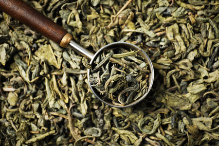 Measuring spoon on dried green tea leaves, top viewの写真素材