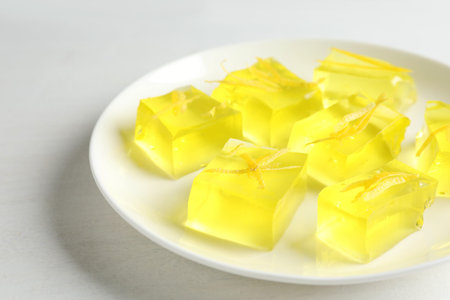 Yummy lemon jelly cubes on white table, closeup
