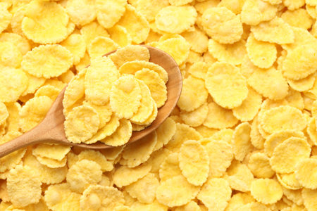 Tasty corn flakes and wooden spoon, top view. Space for text