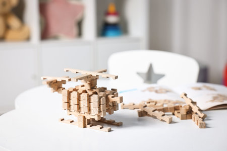 Helicopter figure made of wooden blocks on white table indoors, closeup